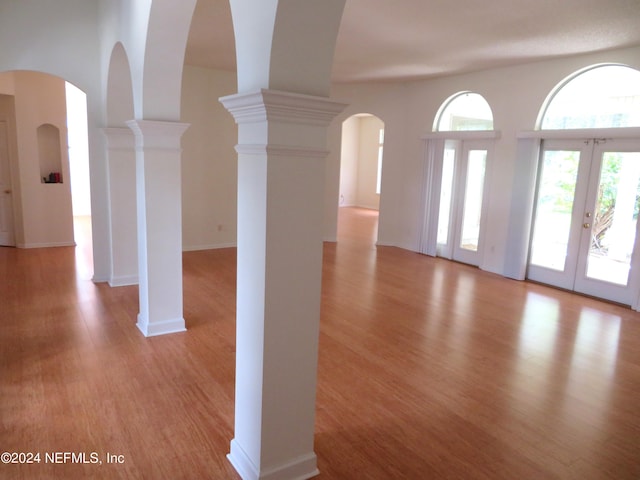 interior space featuring light hardwood / wood-style floors, french doors, and ornate columns