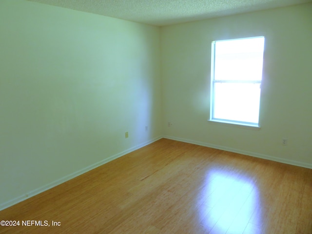 spare room with a textured ceiling and light hardwood / wood-style floors