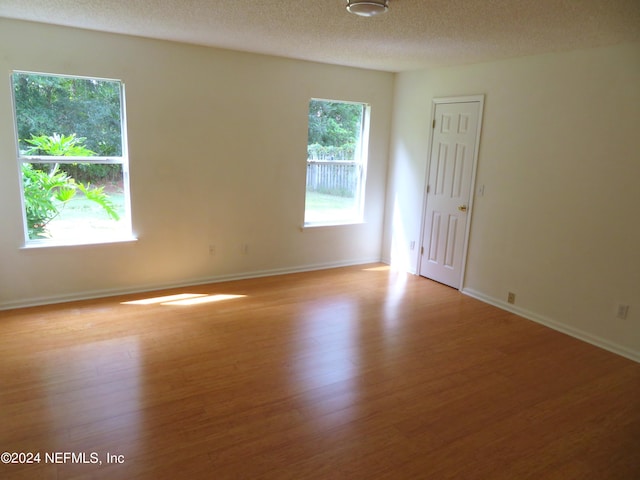 spare room featuring a textured ceiling and light hardwood / wood-style floors