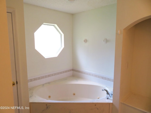 bathroom featuring a textured ceiling and a tub