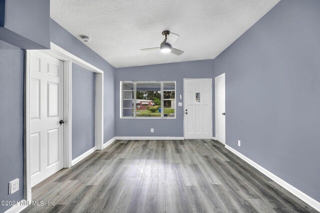 spare room featuring a textured ceiling, wood-type flooring, ceiling fan, and lofted ceiling