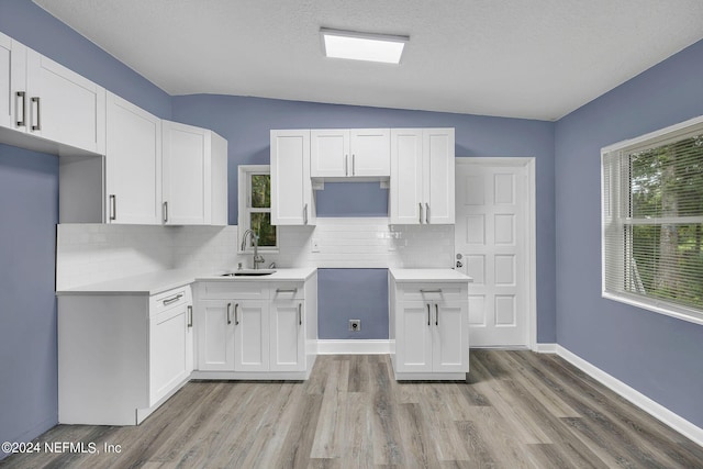 2916 Lippia Rd, Jacksonville, FL 32209 - kitchen featuring decorative backsplash, white cabinetry, a sink, and light wood-style floors