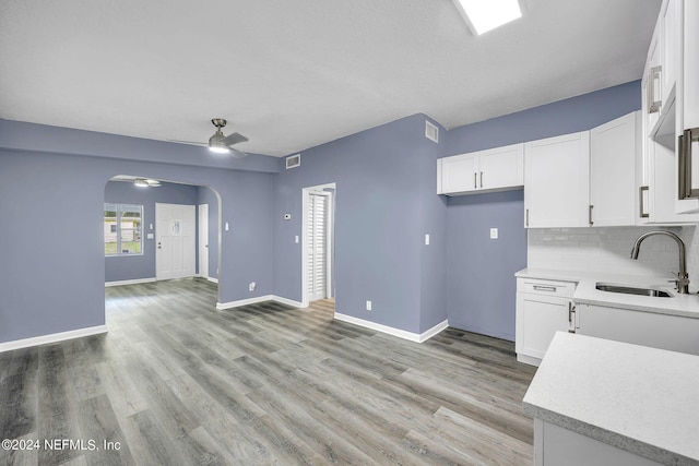 2916 Lippia Rd, Jacksonville, FL 32209 - kitchen with light countertops, a sink, white cabinets, arched walkways, and ceiling fan