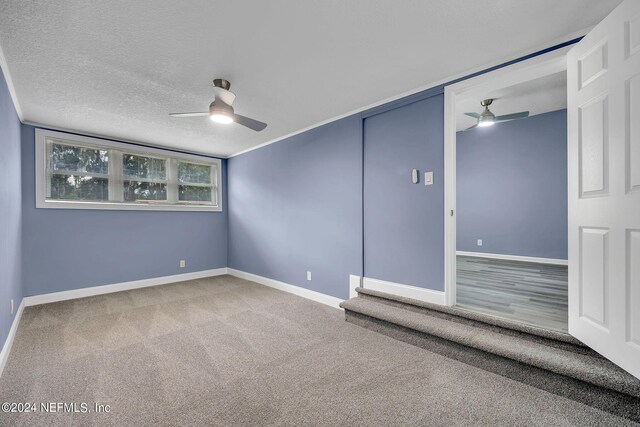 carpeted spare room with ceiling fan and a textured ceiling