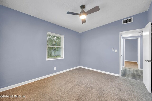 carpeted empty room featuring ceiling fan and a textured ceiling