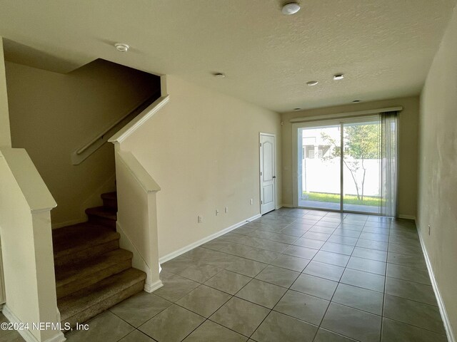 spare room featuring a textured ceiling and light tile patterned floors