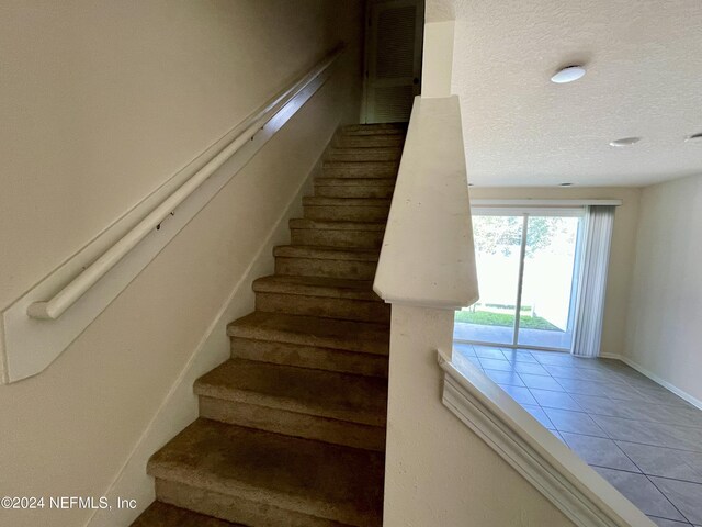 stairs featuring a textured ceiling and tile patterned flooring