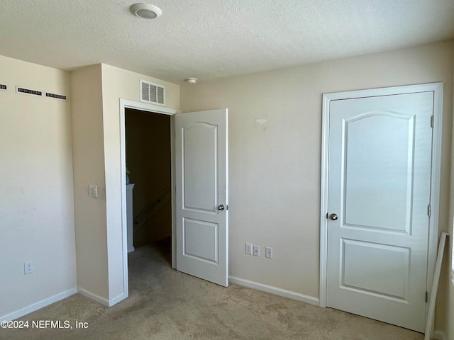 unfurnished bedroom with light carpet and a textured ceiling