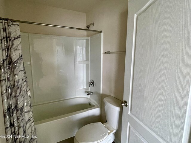 bathroom featuring toilet and shower / tub combo with curtain