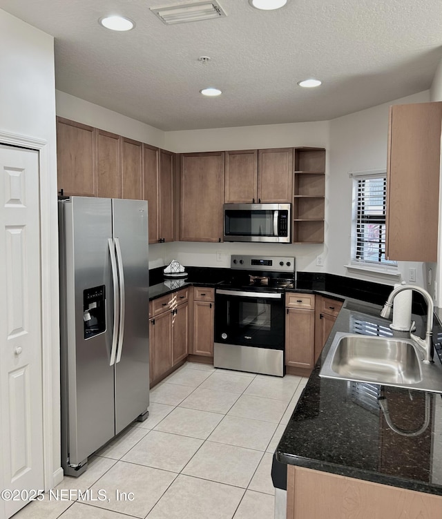 kitchen featuring a textured ceiling, light tile patterned flooring, sink, and stainless steel appliances