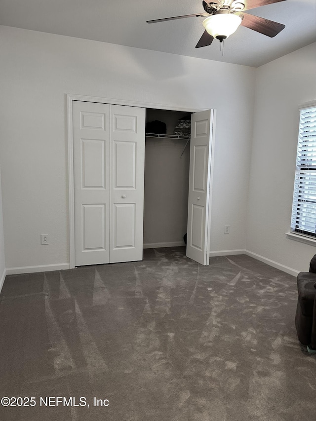 unfurnished bedroom featuring a closet, dark carpet, and ceiling fan