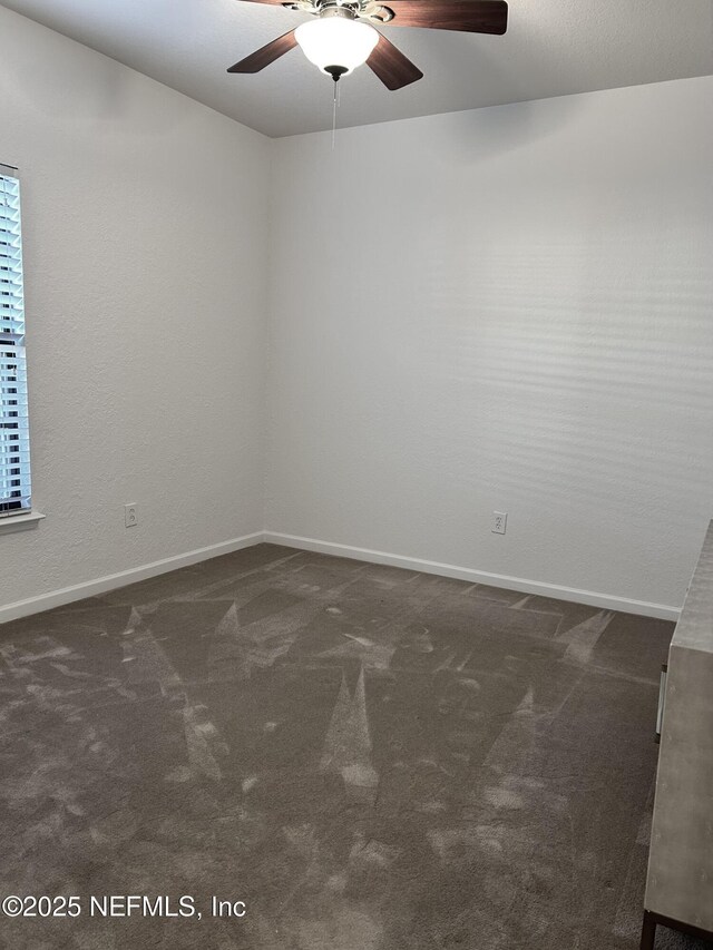 spare room with dark carpet and ceiling fan