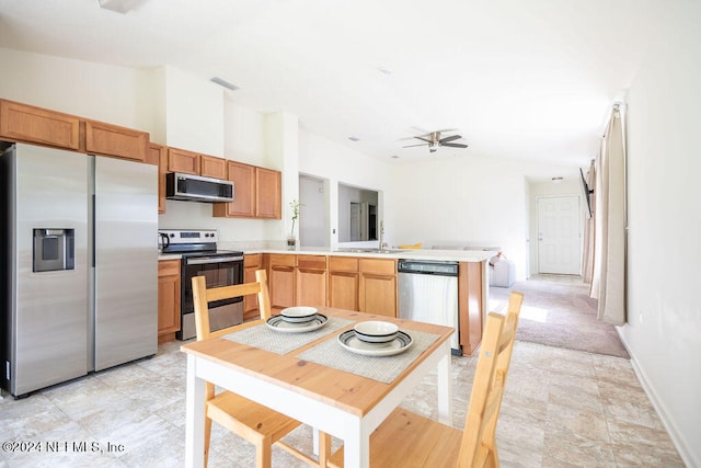 kitchen with ceiling fan, stainless steel appliances, kitchen peninsula, and vaulted ceiling