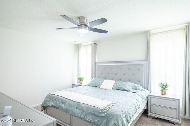 carpeted bedroom with ceiling fan and a textured ceiling