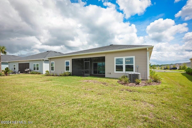 rear view of property with central air condition unit, a yard, and a sunroom