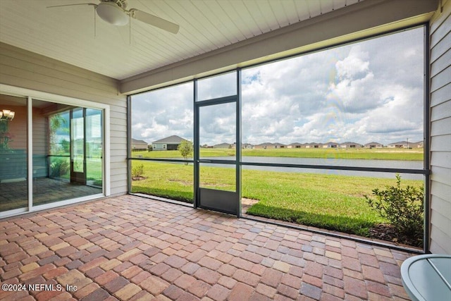 unfurnished sunroom with ceiling fan and a water view