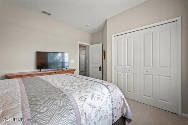 bedroom featuring a textured ceiling, a closet, and light carpet