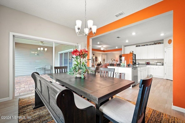 dining area featuring light wood-type flooring, a textured ceiling, and an inviting chandelier