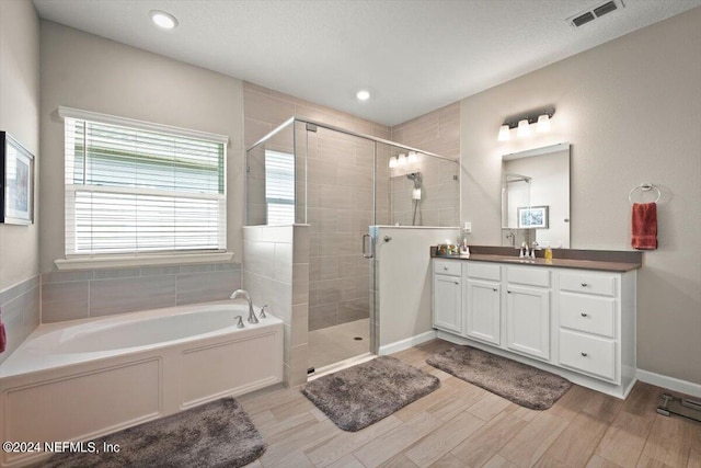 bathroom with vanity, a textured ceiling, hardwood / wood-style floors, and independent shower and bath