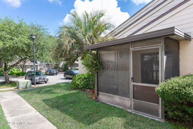 view of property exterior with a yard and a sunroom