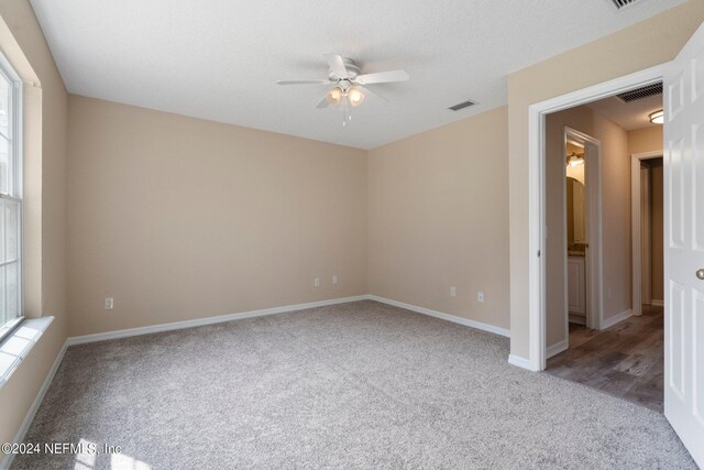 unfurnished bedroom featuring multiple windows, a textured ceiling, ceiling fan, and carpet