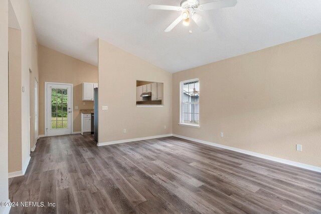 unfurnished room with ceiling fan, vaulted ceiling, baseboards, and wood finished floors