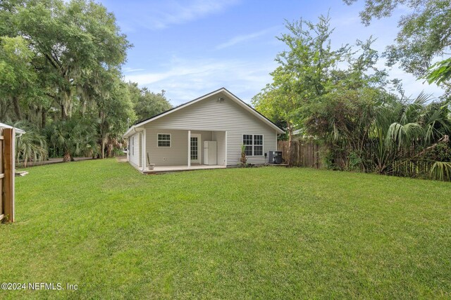 rear view of house featuring cooling unit, a yard, and a patio area