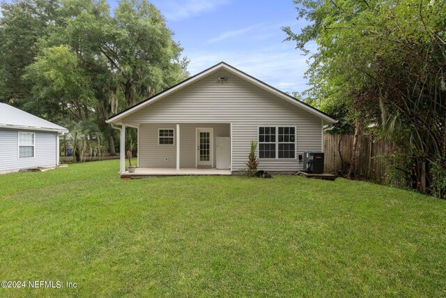 rear view of property featuring central AC unit, a yard, and a patio