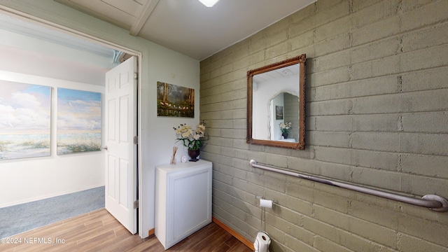 laundry area featuring light hardwood / wood-style flooring and brick wall