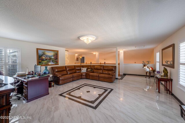 living area with baseboards, marble finish floor, a textured ceiling, and a healthy amount of sunlight