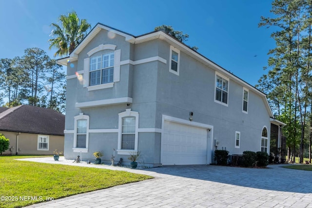 2518 Willow Creek Dr, Fleming Island, FL 32003 - view of side of home featuring stucco siding, an attached garage, a lawn, and decorative driveway
