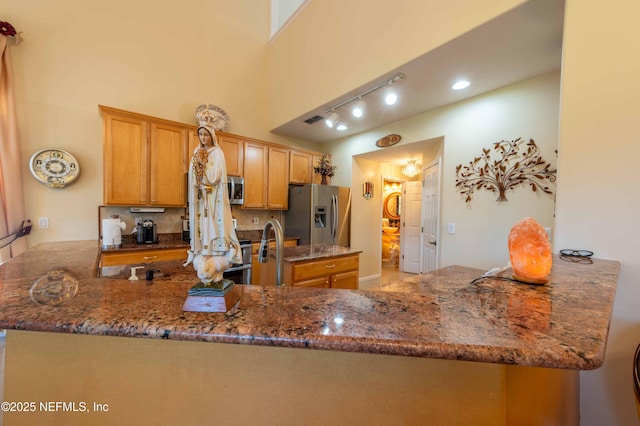 2518 Willow Creek Dr, Fleming Island, FL 32003 - kitchen with visible vents, dark stone counters, stainless steel appliances, decorative backsplash, and brown cabinets