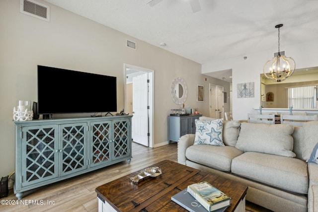 living room featuring ceiling fan with notable chandelier and light hardwood / wood-style floors