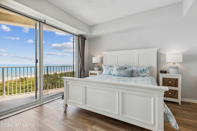 bedroom featuring access to exterior, a water view, and wood-type flooring