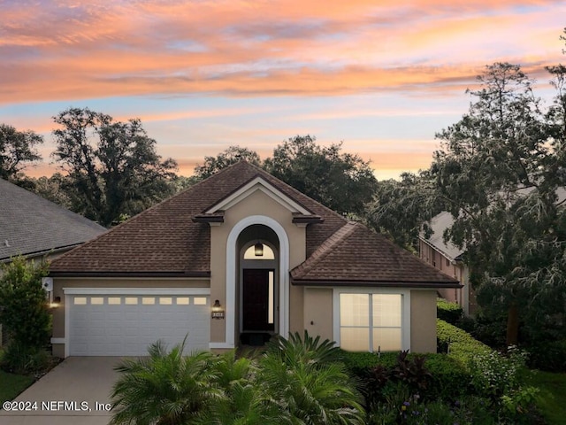 view of front of property with concrete driveway, an attached garage, and stucco siding