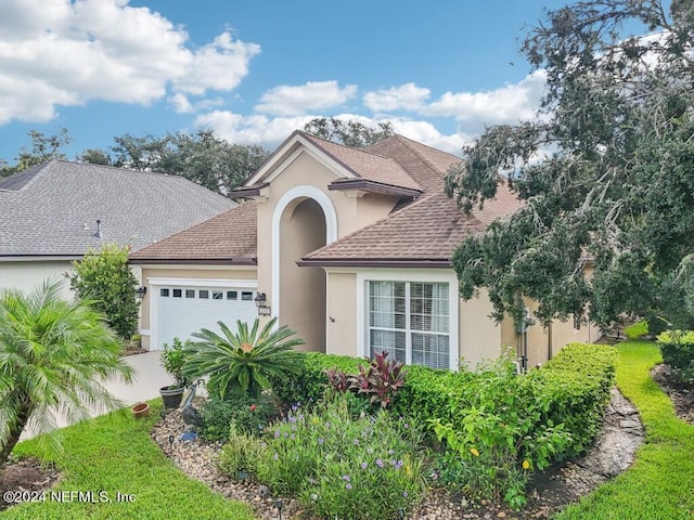 view of front of property featuring an attached garage, driveway, a shingled roof, and stucco siding