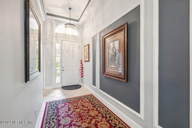 entrance foyer featuring a tray ceiling, light tile patterned floors, and a notable chandelier