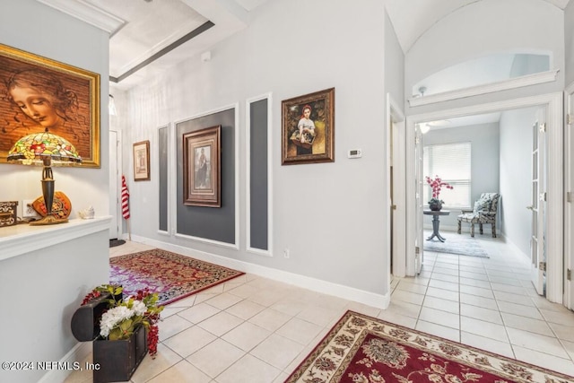 hallway featuring a tray ceiling, baseboards, and light tile patterned floors