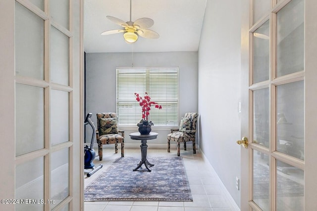 living area featuring lofted ceiling, a ceiling fan, baseboards, french doors, and tile patterned floors