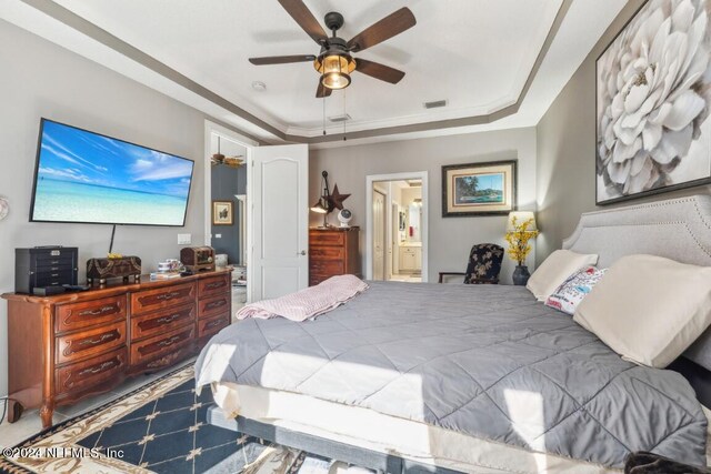 bedroom featuring a tray ceiling, ceiling fan, connected bathroom, and carpet