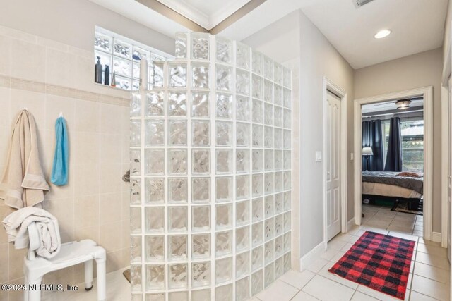 bathroom with tile patterned flooring, tile walls, ornamental molding, and walk in shower