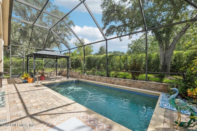 view of swimming pool with glass enclosure, a patio area, and a gazebo