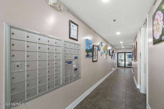 corridor with dark tile patterned flooring and a mail area