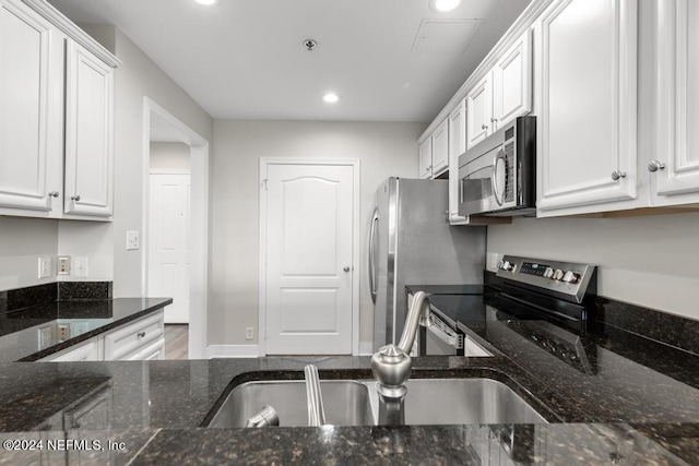 kitchen featuring dark stone counters, wood-type flooring, sink, appliances with stainless steel finishes, and white cabinets