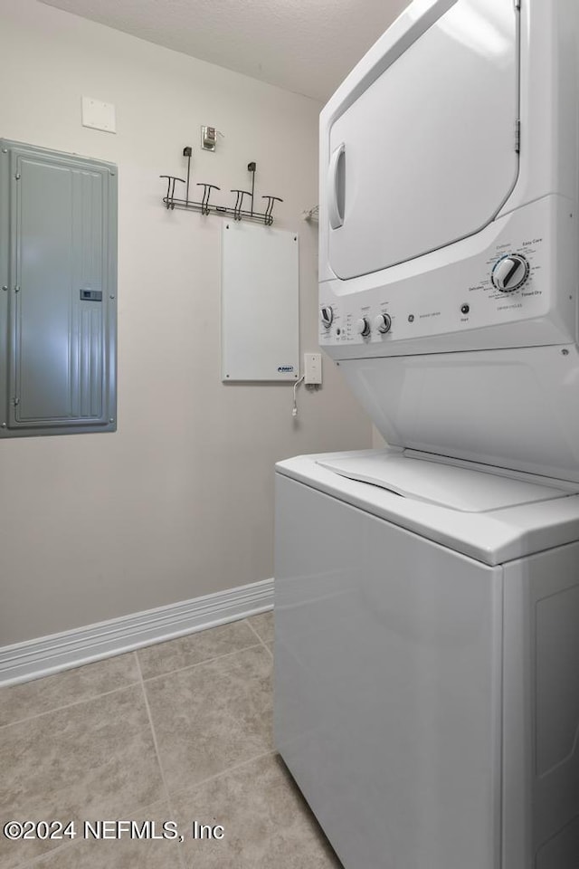 washroom featuring light tile patterned floors, electric panel, and stacked washer and dryer