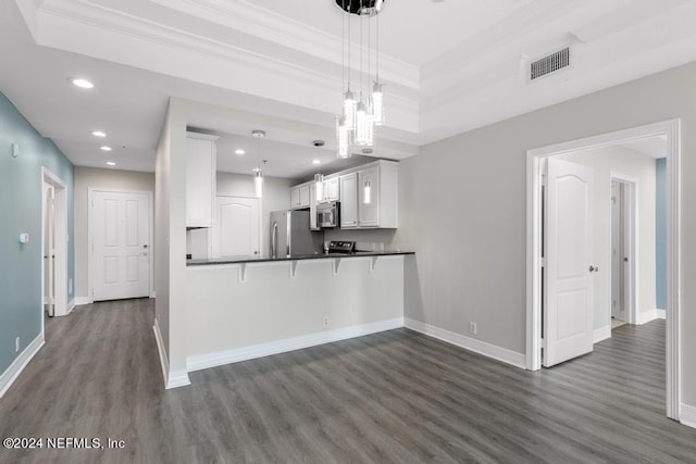 kitchen featuring white cabinets, hanging light fixtures, appliances with stainless steel finishes, dark hardwood / wood-style floors, and ornamental molding