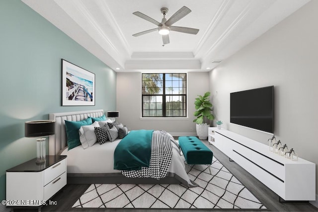 bedroom featuring a raised ceiling, ceiling fan, ornamental molding, and hardwood / wood-style flooring