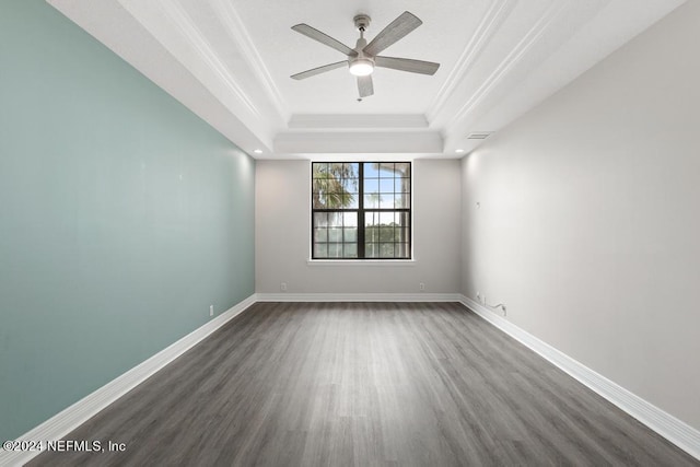 empty room featuring ceiling fan, a tray ceiling, and dark hardwood / wood-style flooring