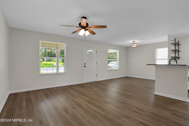 unfurnished living room with ceiling fan and dark wood-type flooring