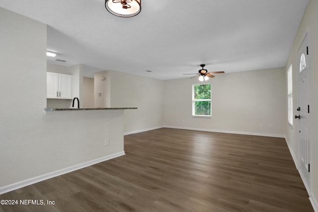 unfurnished living room with dark hardwood / wood-style flooring and ceiling fan